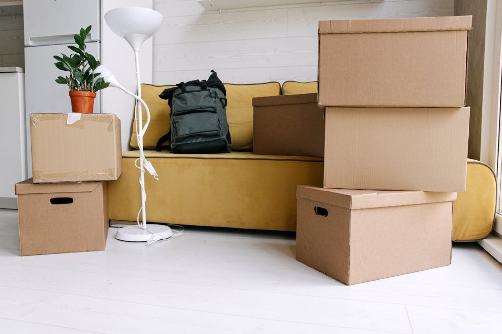 Cardboard boxes and a backpack in a cozy living room signify moving day excitement.