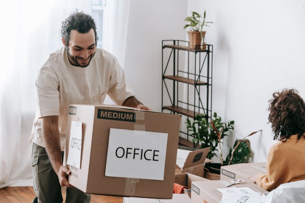 A joyful couple packing boxes labeled office in their home, preparing to move.