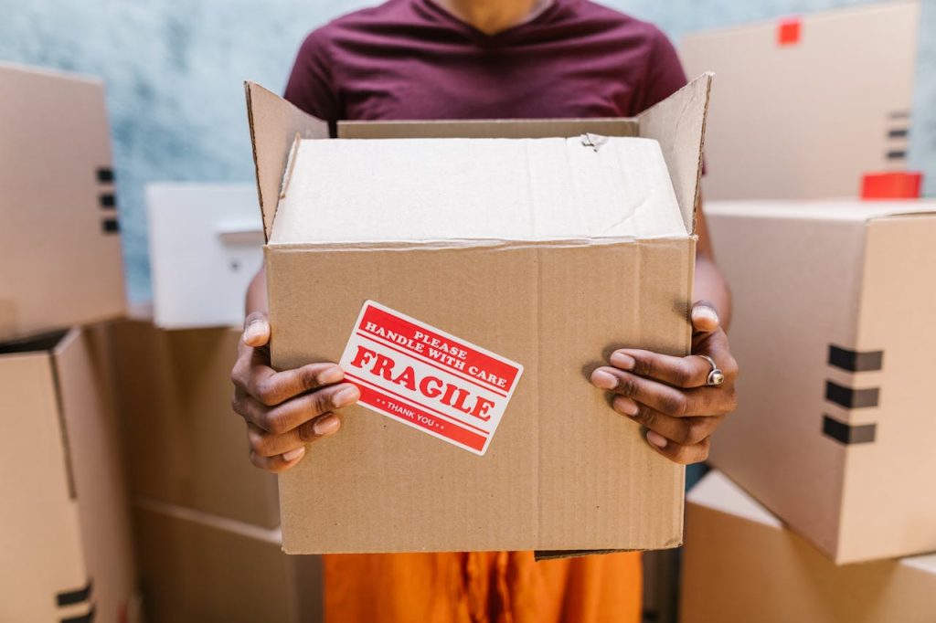 A person holding a cardboard box labeled Fragile during a moving process indoors.
